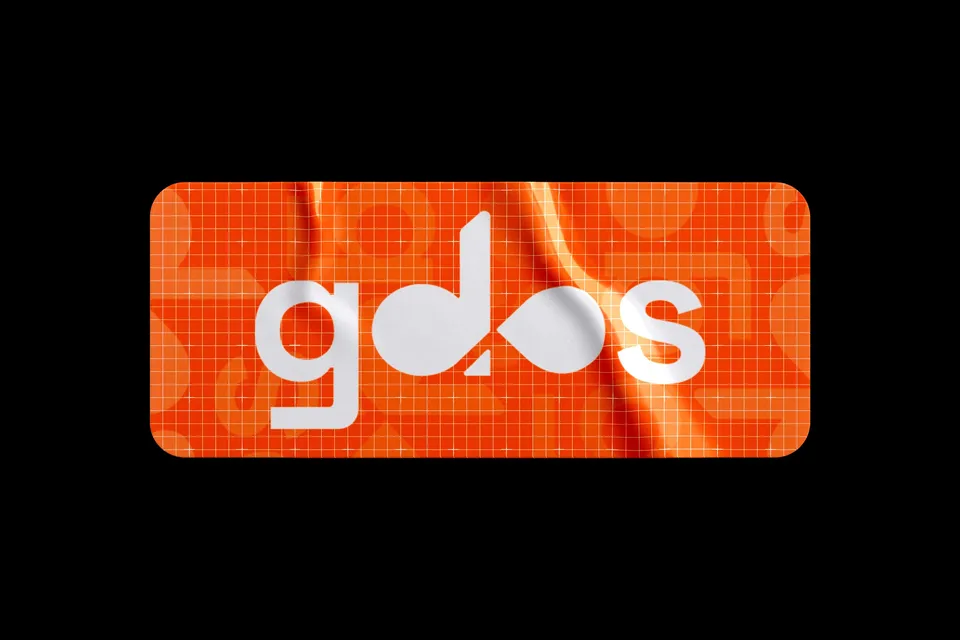 Gilde DevOps Solutions gdos sticker mockup, white lettering on an orange gridded surface against black.