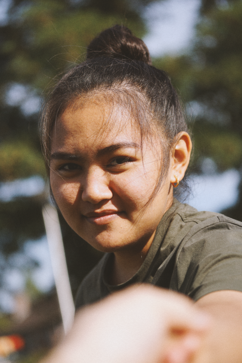 A photo of a filipina girl looking directly at the camera, smiling towards the camera, holding hands with the photographer.