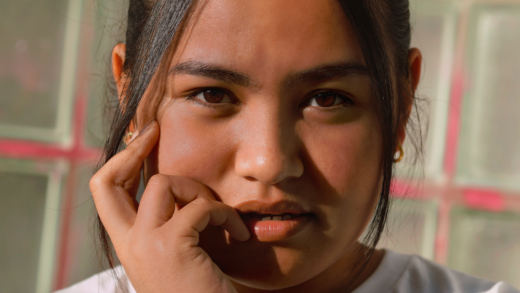 A photo of a filipina girl looking directly at the camera, posing with a smug face, hand on her left cheek.